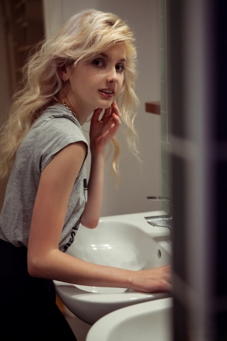 Tiny titted blonde Angelik peels off her clothes to spread naked at her desk