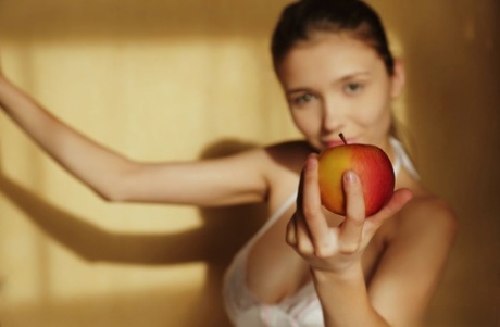 Beautiful teen girl reveals her big tits and bald twat while eating fruit
