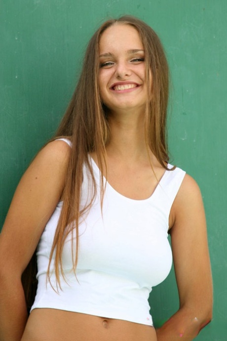 Beautiful young girl with long hair poses in a tank top and bikini bottoms