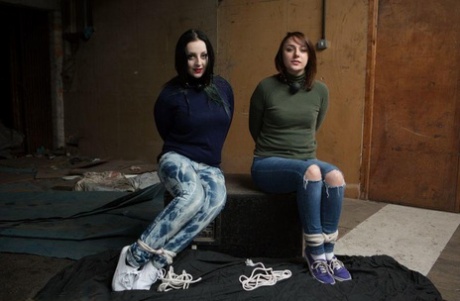 Two white girls are hogtied and ball gagged in sweaters and jeans