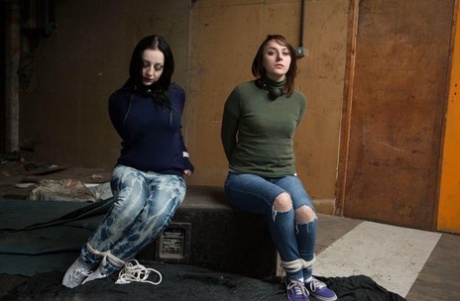 Two white girls are hogtied and ball gagged in sweaters and jeans