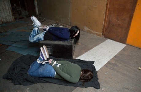 Two white girls are hogtied and ball gagged in sweaters and jeans