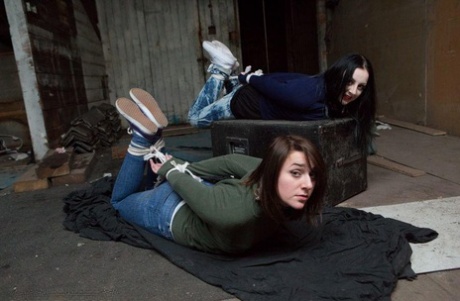 Two white girls are hogtied and ball gagged in sweaters and jeans