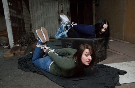 Two white girls are hogtied and ball gagged in sweaters and jeans
