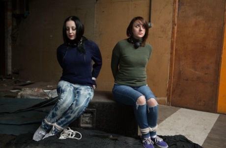 Two white girls are hogtied and ball gagged in sweaters and jeans