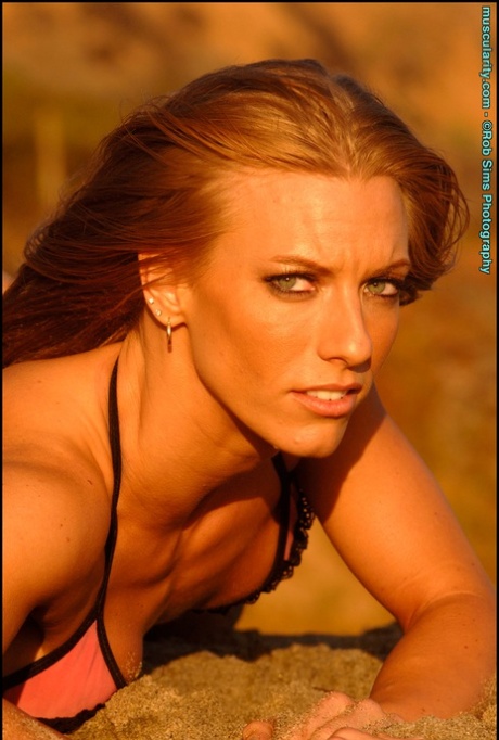 Bodybuilder Courtney Schwartzmeyer poses on a beach in a bikini