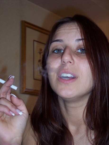 Totally naked girl Lexxxi sits on her bed while smoking a cigarette