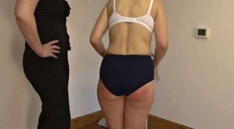 Brunette chick has her ass turned red during a spanking from a woman