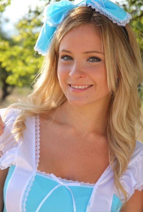 Cute blonde Elle Richie removes her cute outfit to pose topless in a field