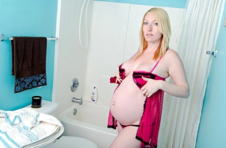 Solo girl shows her heavily pregnant belly while taking a shower