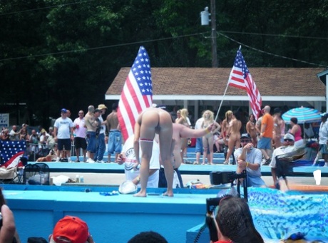 Female strippers get naked on an outdoor stage at a clothing optional club