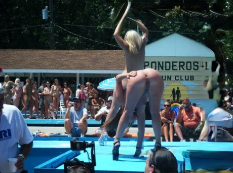 Female strippers get naked on an outdoor stage at a clothing optional club