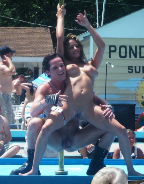 Female strippers get naked on an outdoor stage at a clothing optional club