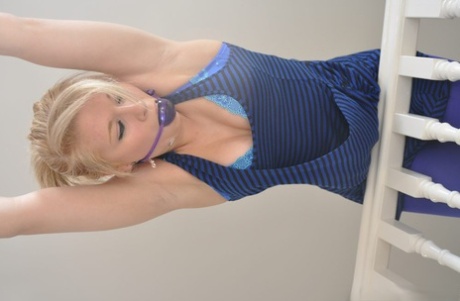 Blonde girl is tied to a banister while fully clothed and ball gagged