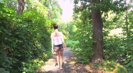 Short taken girl Ali Bordeaux takes a pee while walking on a path in the woods