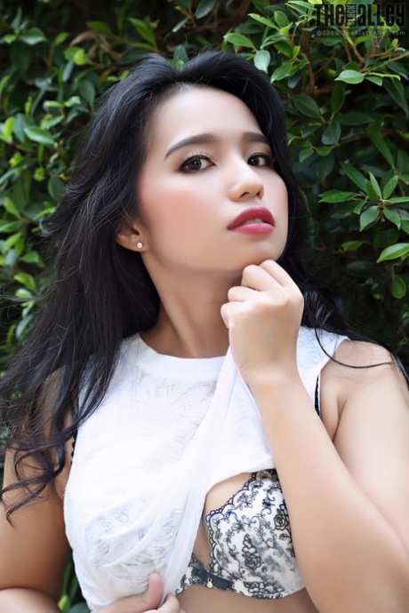 Beautiful Asian girl Norah gets totally naked next to a hedge in a garden