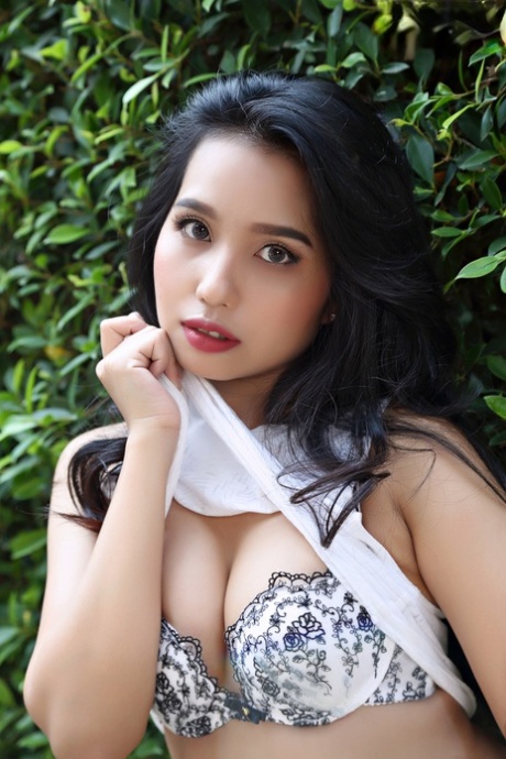 Beautiful Asian girl Norah gets totally naked next to a hedge in a garden