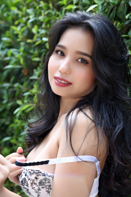 Beautiful Asian girl Norah gets totally naked next to a hedge in a garden