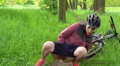 Solo girl Antonia Sainz squats for a pee while biking on a path in the woods