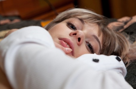 Young blonde Queva poses nude on a bed with her shirt unbuttoned