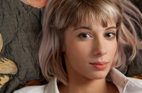 Young blonde Queva poses nude on a bed with her shirt unbuttoned