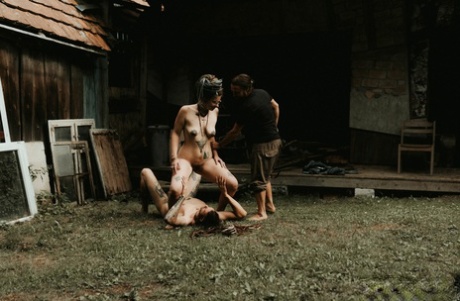 Heavily tattooed girls piss on a naked man outside the back steps of a house