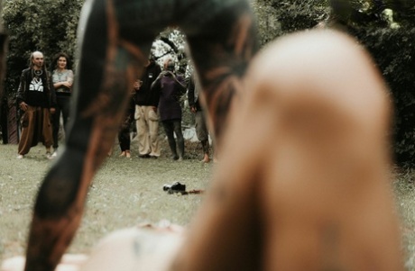 Heavily tattooed girls piss on a naked man outside the back steps of a house