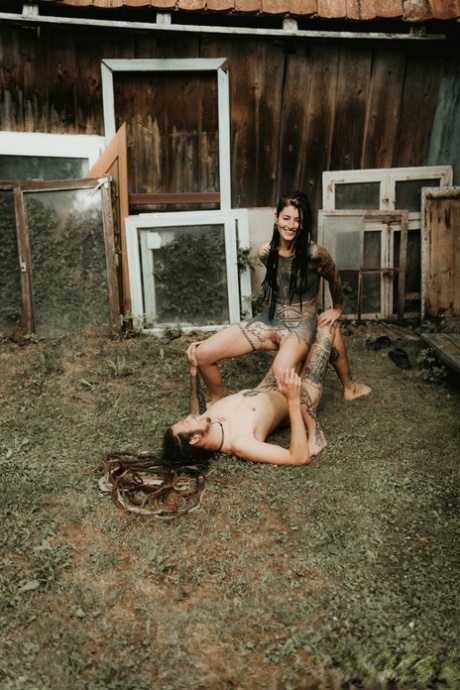Heavily tattooed girls piss on a naked man outside the back steps of a house