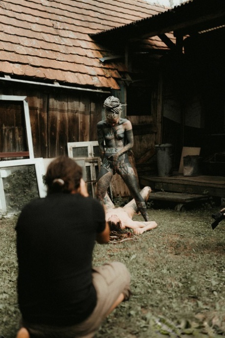 Heavily tattooed girls piss on a naked man outside the back steps of a house