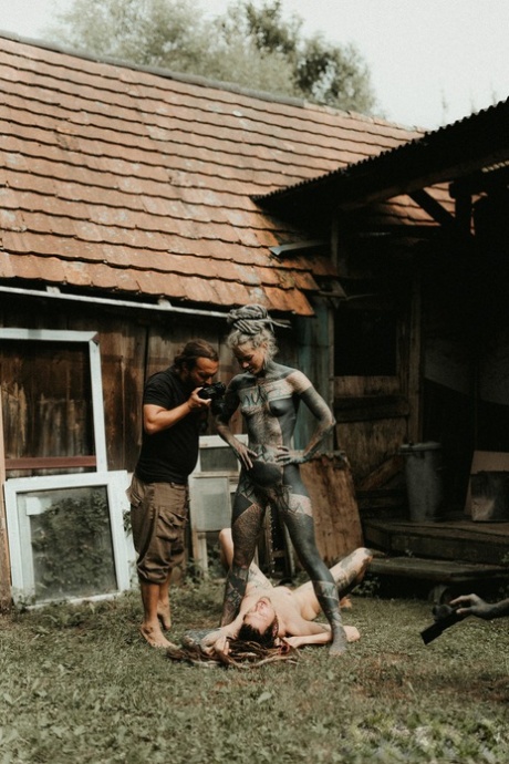 Heavily tattooed girls piss on a naked man outside the back steps of a house