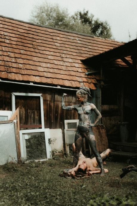 Heavily tattooed girls piss on a naked man outside the back steps of a house