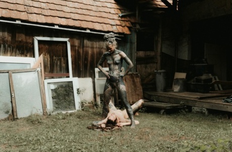 Heavily tattooed girls piss on a naked man outside the back steps of a house