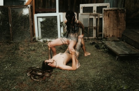 Heavily tattooed girls piss on a naked man outside the back steps of a house