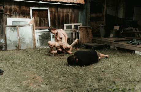Heavily tattooed girls piss on a naked man outside the back steps of a house