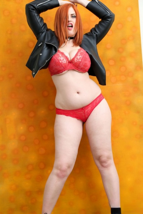 Sexy redhead Alexsis Faye licks her lips while loosing her hooters