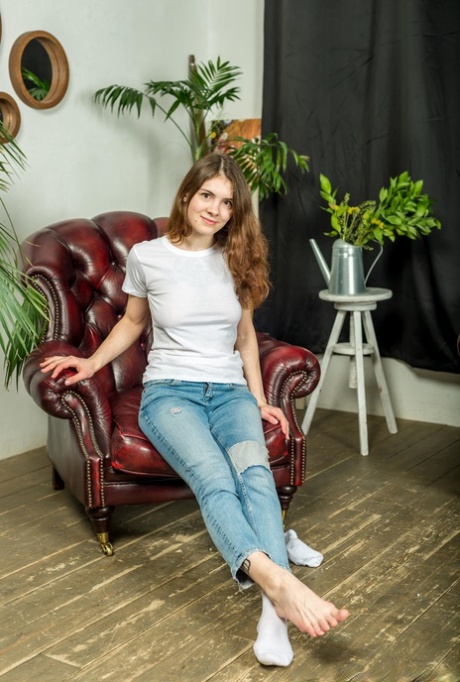 Girl next door type shows the bottoms of her feet in faded jeans