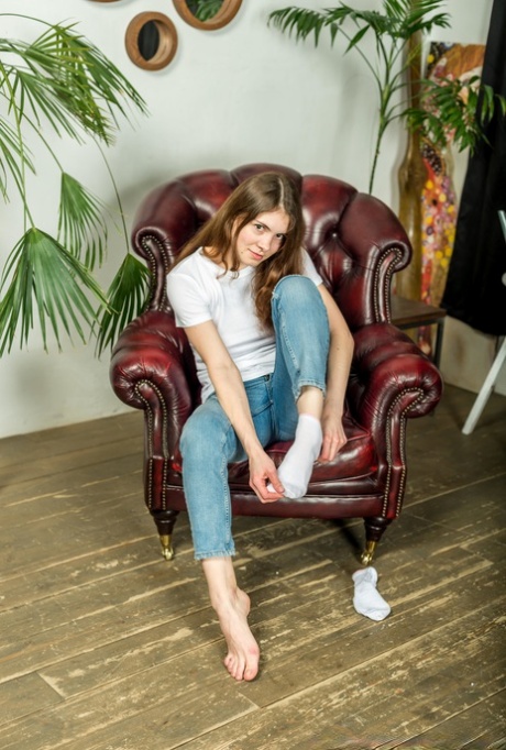 Girl next door type shows the bottoms of her feet in faded jeans