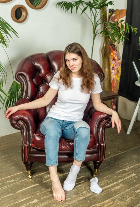 Girl next door type shows the bottoms of her feet in faded jeans