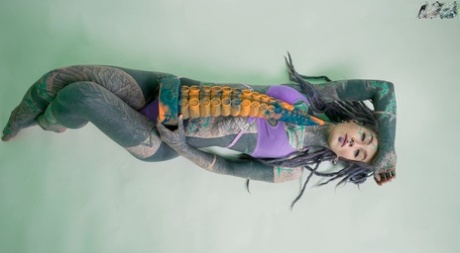 Heavily tattooed girl Anuskatzz holds a couple of taintacle toys in the nude