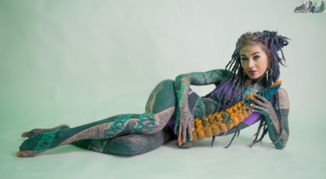 Heavily tattooed girl Anuskatzz holds a couple of taintacle toys in the nude