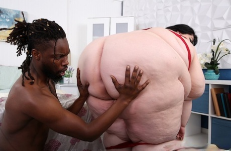 Dark-haired SSBBW Kass The Blast engages in interracial sex on a bed