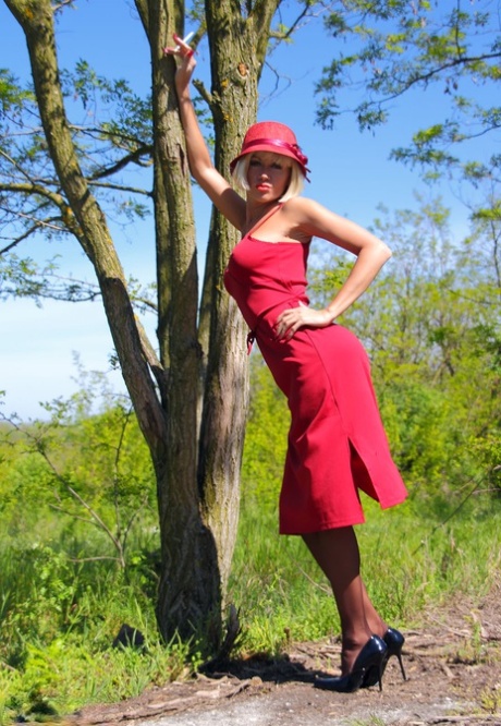 Blonde MILF Eva Diangelo shows tits and nice ass against a tree in nylons