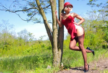 Blonde MILF Eva Diangelo shows tits and nice ass against a tree in nylons