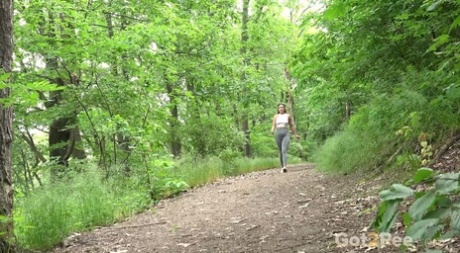 Caucasian girl Julia North pulls down leggings to pee on a path in the woods