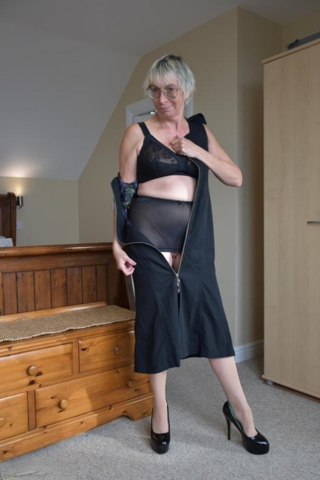 Naked British woman Barby Slut gets dressed on a trunk in her bedroom
