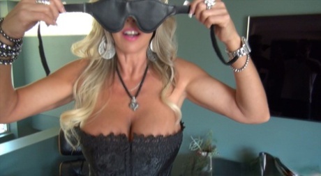 Hot mature lady in lingerie and stockings slipping on a blindfold