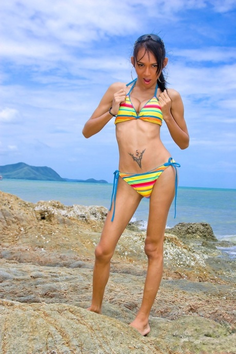 Shemale model Mint strips her bikini on the beach and strokes her huge boner