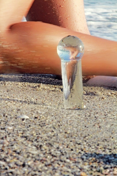 Naughty teen Layla toys with a dildo while playing naked on the beach