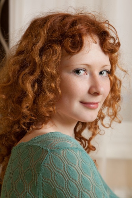 Curly-haired redhead Rochelle exposes her sexy body and poses on her bed