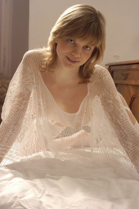 Sexy blonde Margo A posing in her see-through white lingerie on the bed